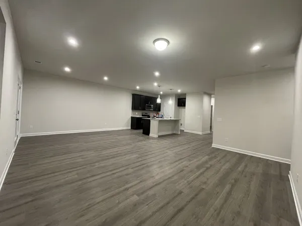 an empty room with wooden floor kitchen kitchen view and windows