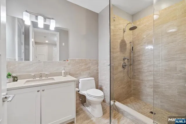 a bathroom with a shower sink vanity mirror and toilet