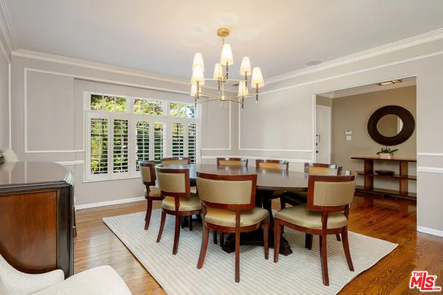 a dining room with wooden floor a chandelier a glass table and chairs