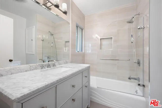 a bathroom with a granite countertop sink mirror and a bathtub