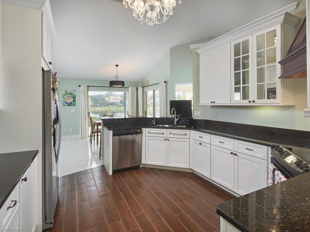 2126 East Crown Pointe Boulevard Naples, FL 34112 - Photo 8 of 26 a kitchen with stainless steel appliances granite countertop a refrigerator a sink dishwasher a stove and white countertops with wooden floor