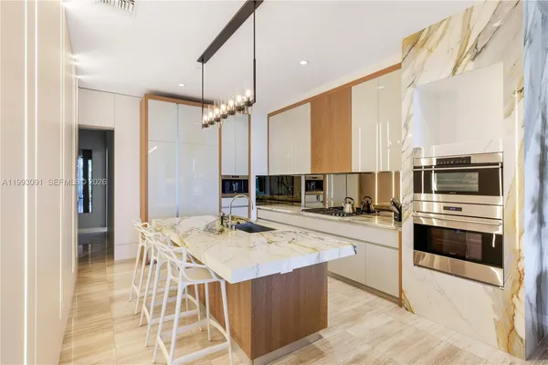 a kitchen with stainless steel appliances kitchen island granite countertop a stove top oven a sink dishwasher a dining table and chairs with wooden floor
