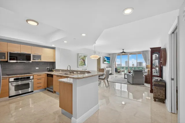 a view of a kitchen with kitchen island a large counter top space a sink stainless steel appliances and cabinets