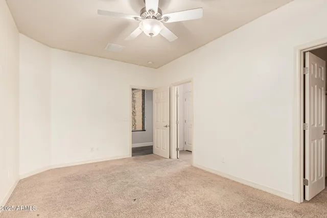 an empty room with a window and a fan