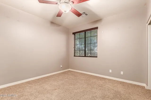 an empty room with closet and a ceiling fan
