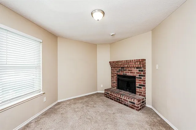 a view of an empty room with a fireplace and a window