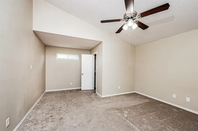 an empty room with a ceiling fan and carpet