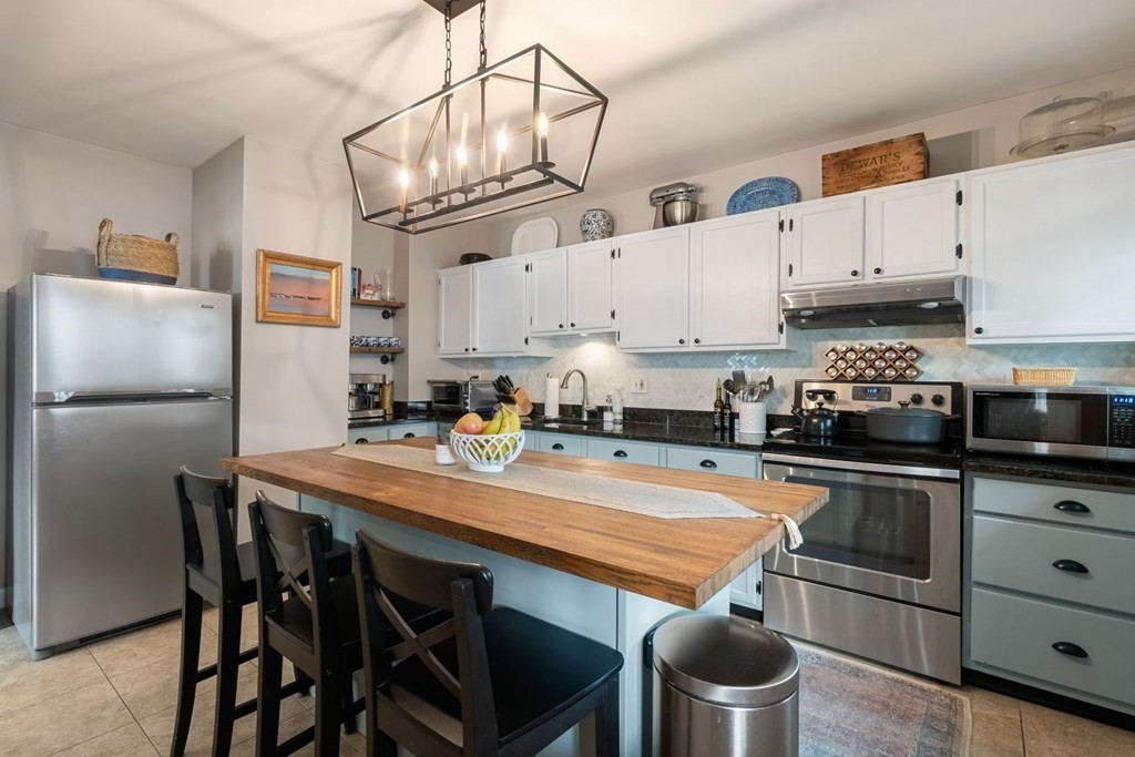 52 O Street, Unit 3 Boston, MA 02127 - Photo 4 of 15 a kitchen with stainless steel appliances a table chairs and a refrigerator