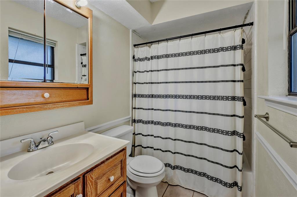 108 Prairie Creek Road Red Oak, TX 75154 - Photo 14 of 19 Bathroom featuring a wood-finish vanity with a white countertop and integrated sink, a mirrored medicine cabinet, and a shower/tub combination with white tile surround