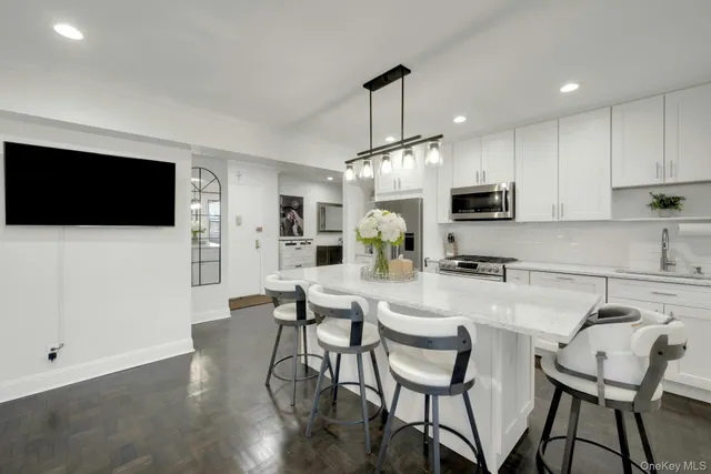 a kitchen with stainless steel appliances a dining table chairs microwave and sink