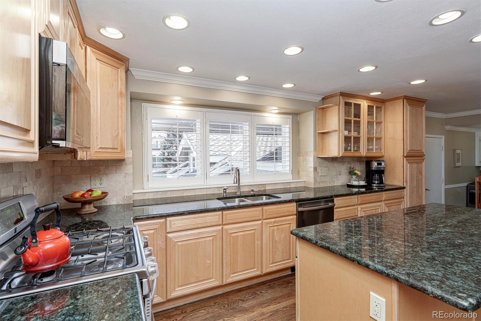6145 South Eudora Way Centennial, CO 80121 - Photo 12 of 33 a kitchen with kitchen island granite countertop a sink and cabinets