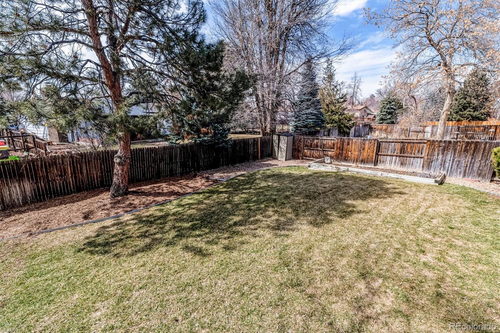 6145 South Eudora Way Centennial, CO 80121 - Photo 30 of 33 a backyard of a house with large trees and wooden fence