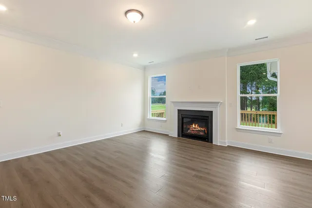 an empty room with wooden floor fireplace and windows