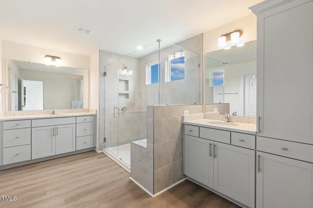 a bathroom with a double vanity sink mirror and shower