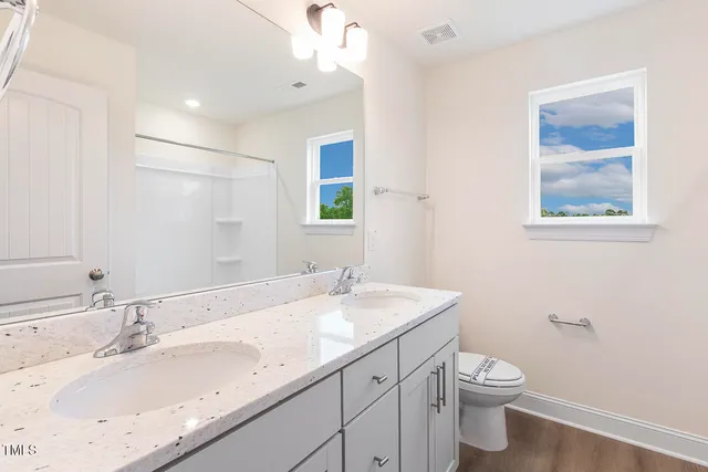 a bathroom with a granite countertop sink mirror vanity and toilet
