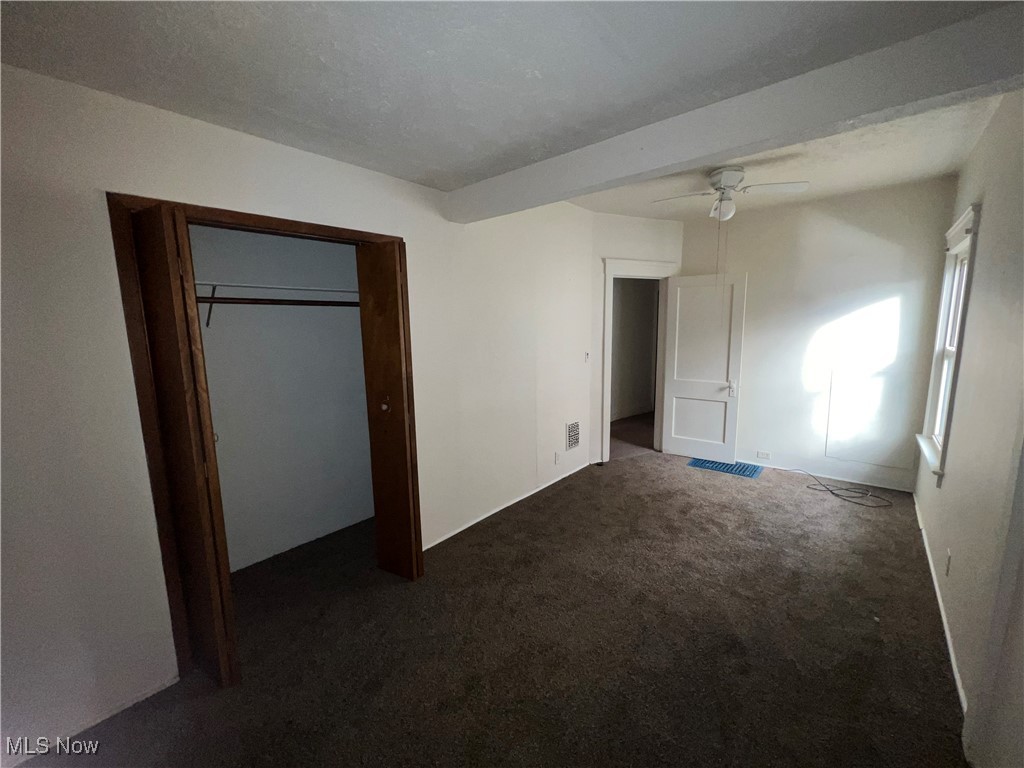 1334 Penhurst Road Cleveland, OH 44110 - Photo 19 of 20 Unfurnished bedroom with a closet, dark carpet, and a ceiling fan