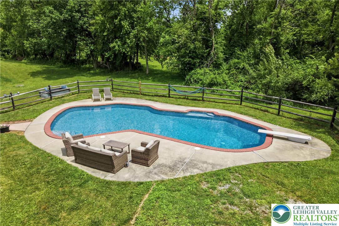 732 Bushkill Center Road Nazareth, PA 18064 - Photo 37 of 43 An inviting pool area with a diving board is surrounded by vibrant green grass and mature trees.