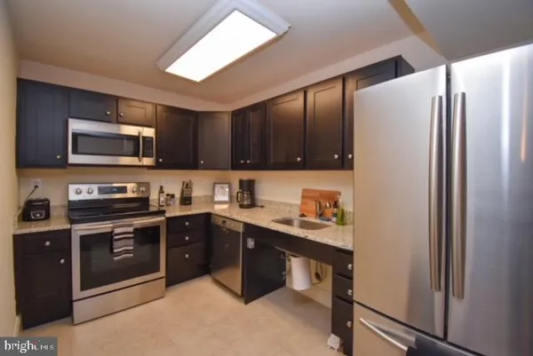 a kitchen with stainless steel appliances granite countertop a refrigerator stove a sink dishwasher and microwave oven