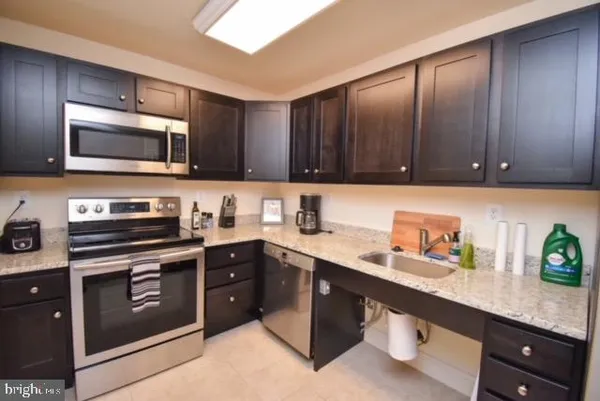 a kitchen with stainless steel appliances granite countertop wooden cabinets a stove a sink and dishwasher