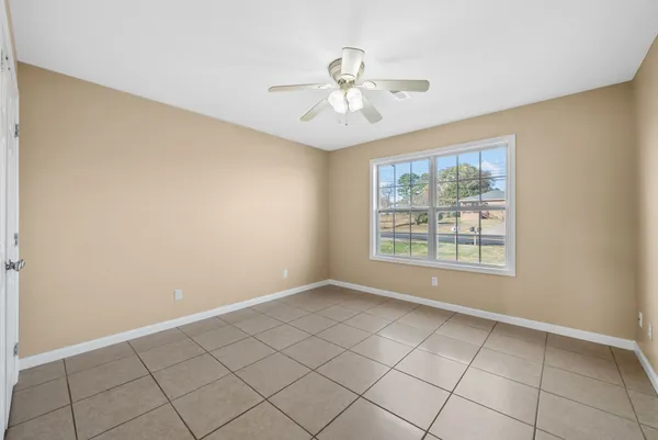a view of an empty room with chandelier fan and fire place