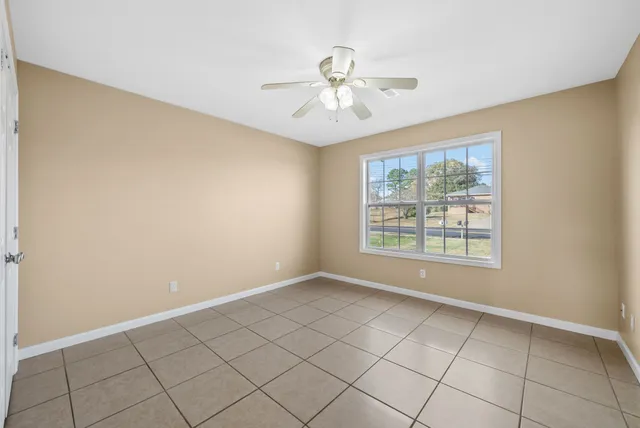 a view of an empty room with chandelier fan and fire place