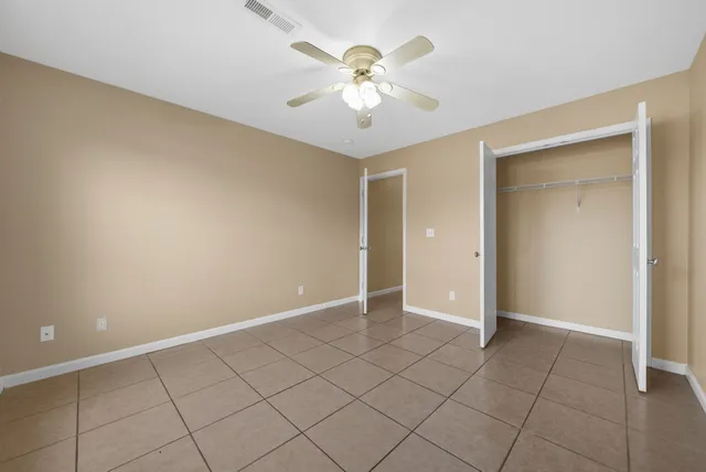 wooden floor in an empty room with a chandelier fan