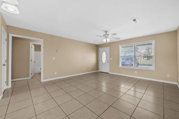 an empty room with windows and fan