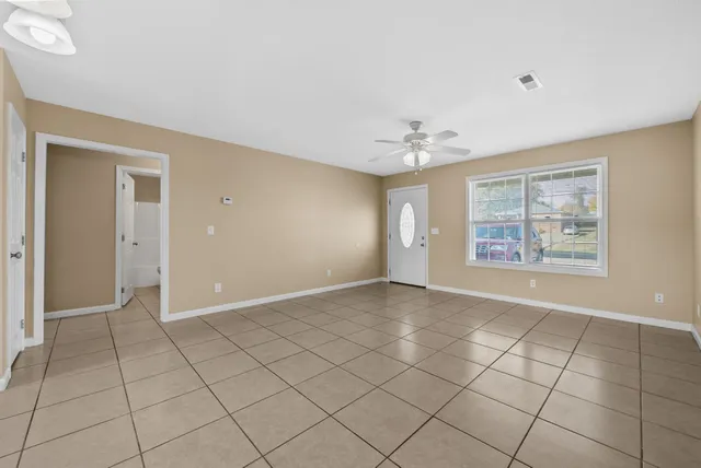 an empty room with windows and fan