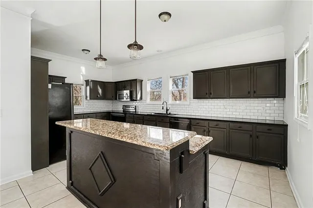 a kitchen with stainless steel appliances granite countertop a sink a stove a refrigerator and a microwave