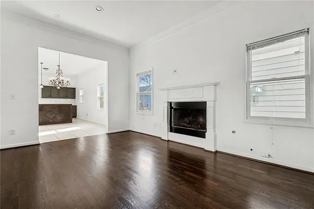 an empty room with wooden floor fireplace and windows