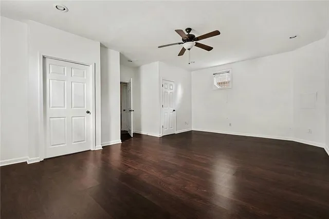 a view of empty room with wooden floor and ceiling fan