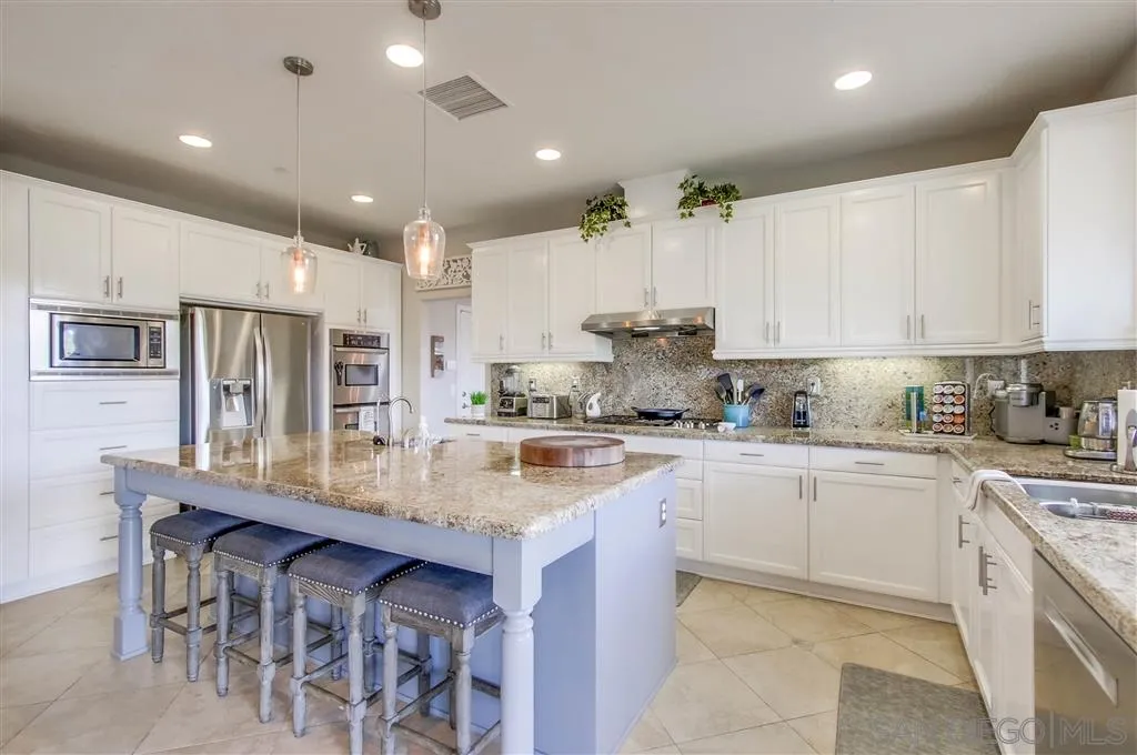 17628 Alva Road San Diego, CA 92127 - Photo 11 of 25 a kitchen with stainless steel appliances granite countertop a table chairs sink and cabinets