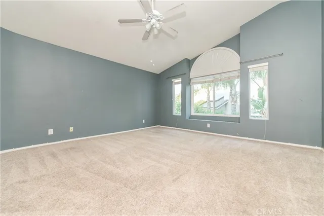 an empty room with windows and ceiling fan
