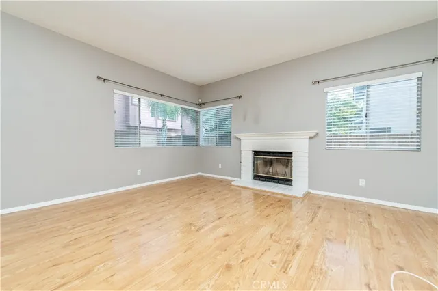 a view of empty room with wooden floor and fireplace