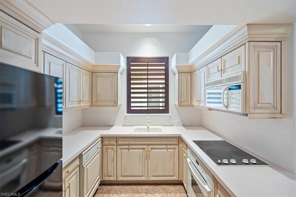 13700 Pondview Circle Naples, FL 34119 - Photo 28 of 49 Kitchen featuring black appliances, light countertops, light brown cabinets, and light tile patterned floors