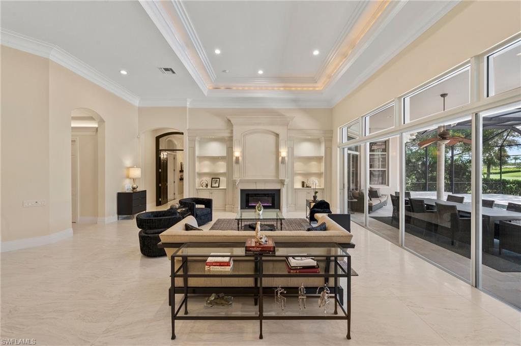 13700 Pondview Circle Naples, FL 34119 - Photo 7 of 49 Living room with arched walkways, built in shelves, a large fireplace, ornamental molding, and recessed lighting