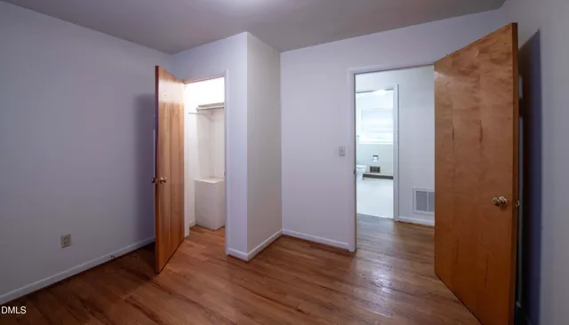 an empty room with wooden floor and a bathroom