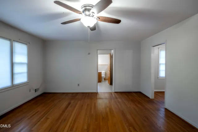 an empty room with wooden floor chandelier fan and windows