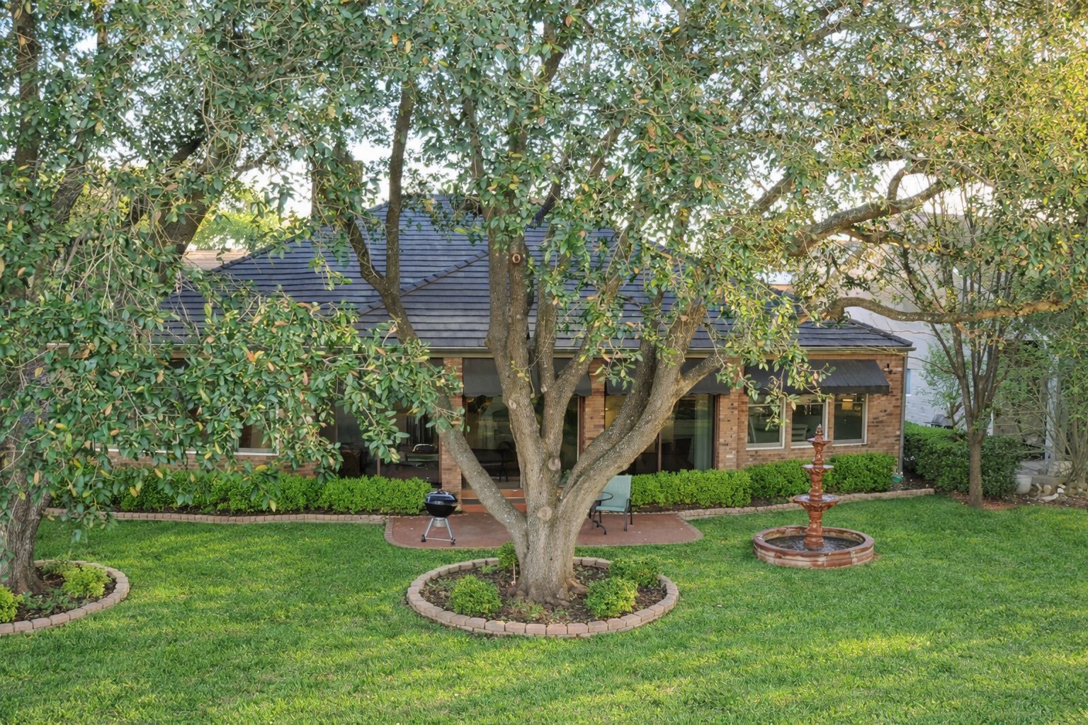 a front view of a house with garden and trees