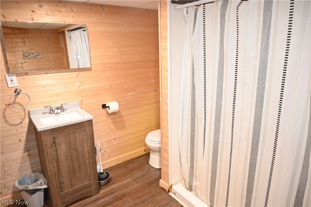 94 North 5th Street Rittman, OH 44270 - Photo 20 of 27 Full bath with wood walls, vanity, a stall shower, and wood style flooring