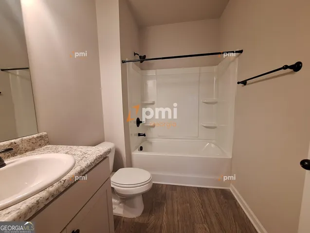 a bathroom with a granite countertop bathtub shower sink vanity and toilet