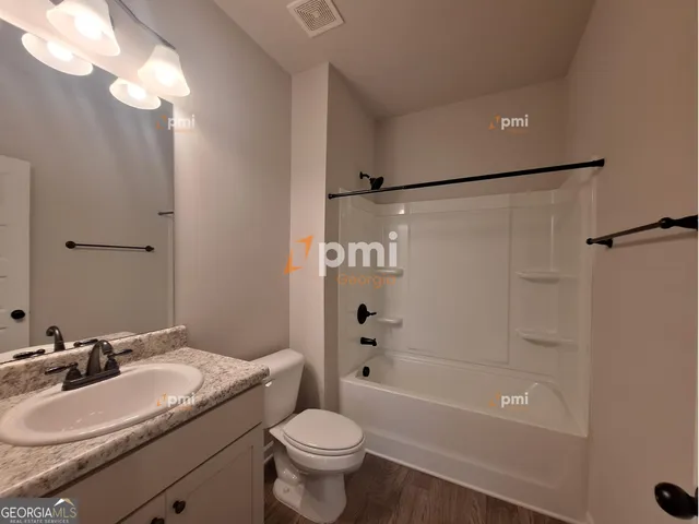 a bathroom with a granite countertop sink a toilet and shower