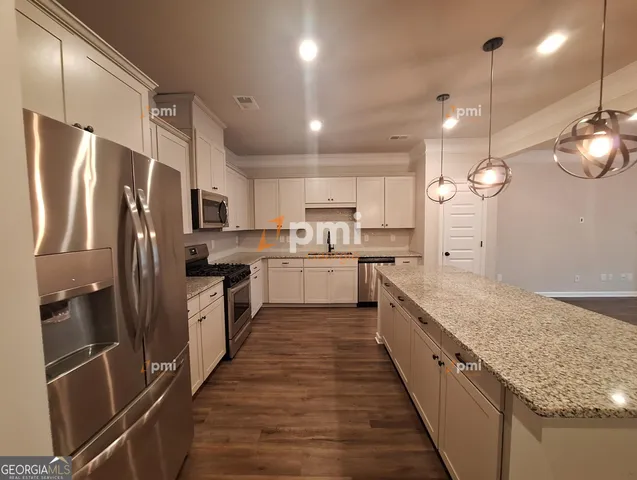 a large kitchen with stainless steel appliances kitchen island a large counter top a refrigerator and a sink