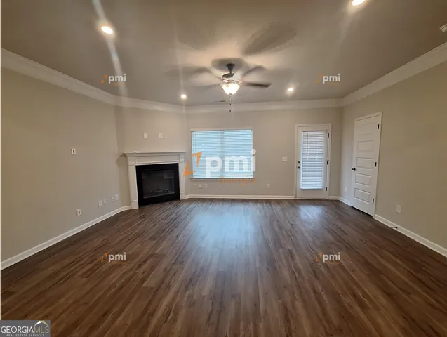 an empty room with wooden floor fireplace and windows