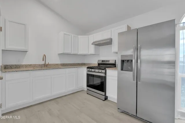 a kitchen with stainless steel appliances granite countertop a refrigerator and a stove top oven