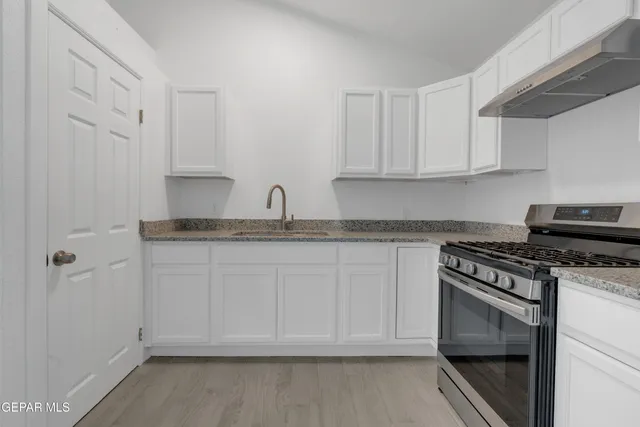 a kitchen with granite countertop white cabinets and a stove