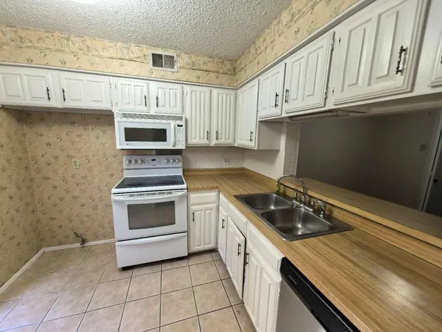 a kitchen with granite countertop a stove sink and cabinets