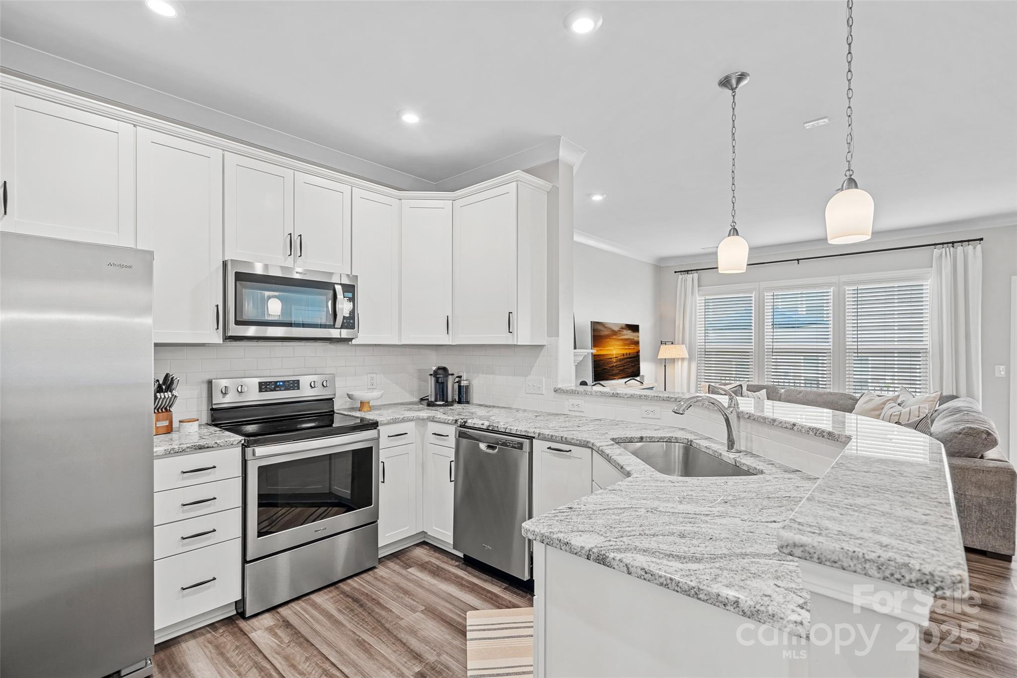 a kitchen with stainless steel appliances granite countertop a sink a stove and a wooden floors