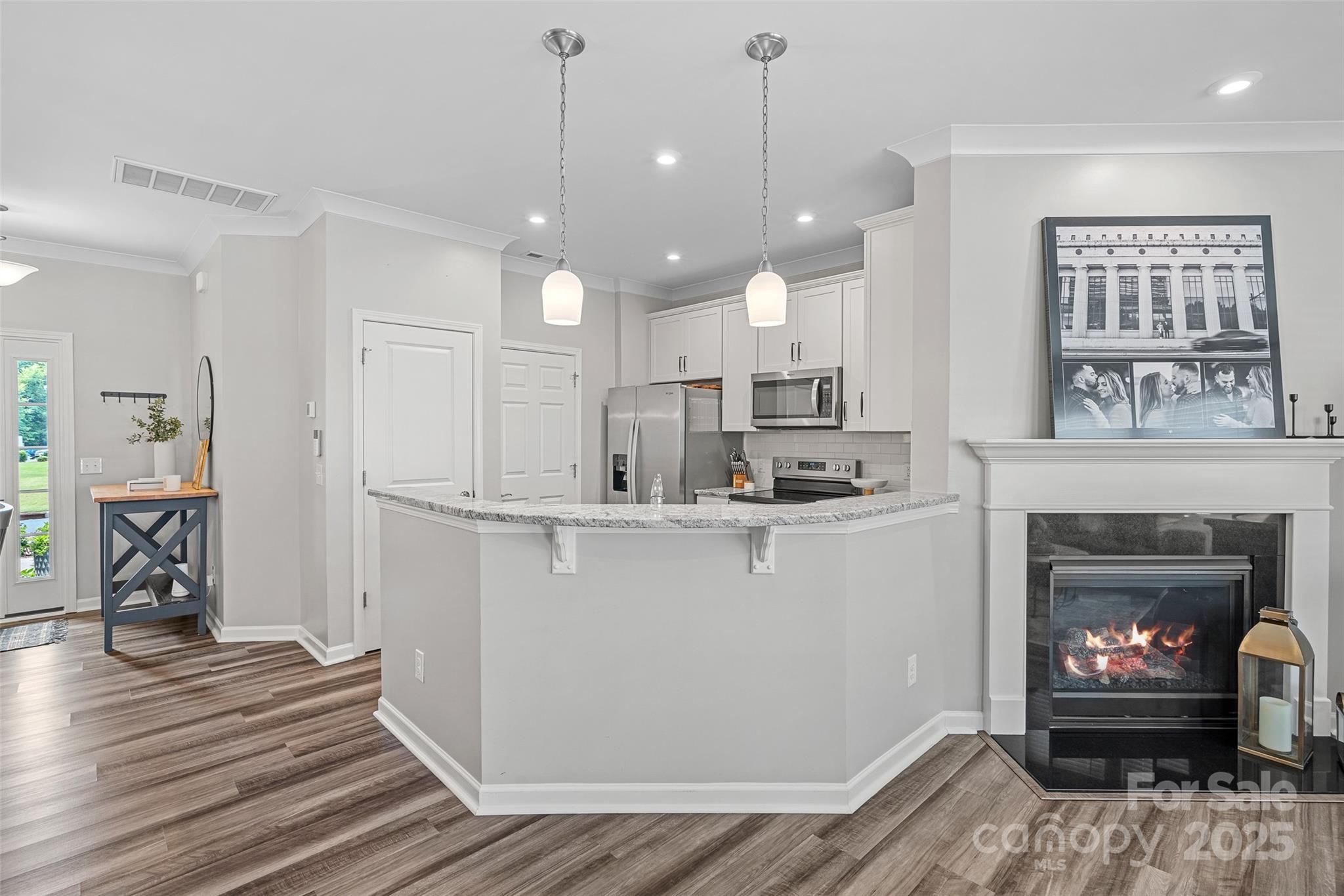 816 Canoe Song Road Fort Mill, SC 29708 - Photo 7 of 26 a open kitchen view with stainless steel appliances granite countertop a refrigerator a fireplace a stove and a fireplace with wooden floor