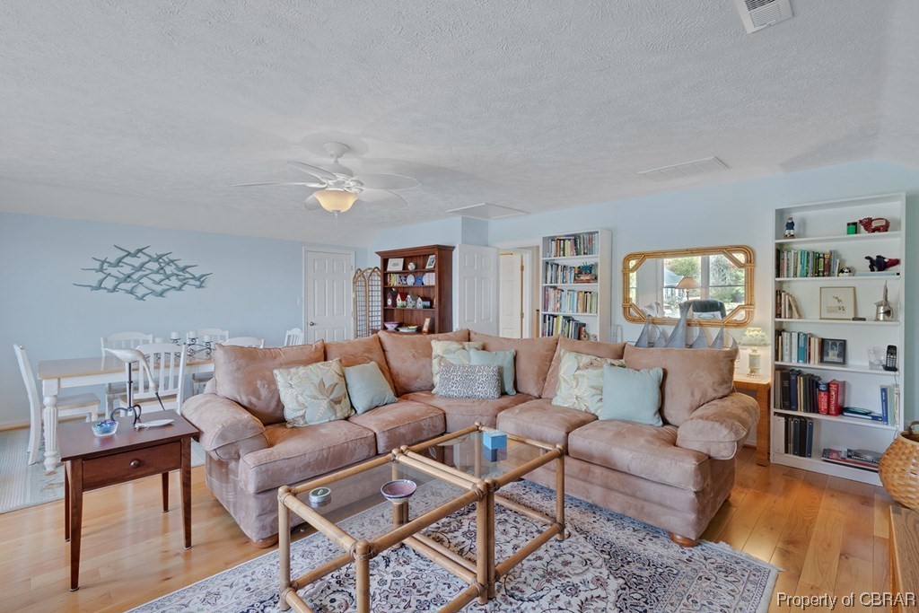 362 Beach Creek Road Lancaster, VA 22503 - Photo 26 of 47 Living room featuring light wood-type flooring, a textured ceiling, and ceiling fan